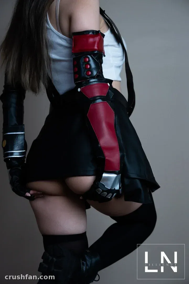 Creator in einem rot-schwarzen Rüstungs-Cosplay-Outfit, posierend vor einem grauen Studiohintergrund.