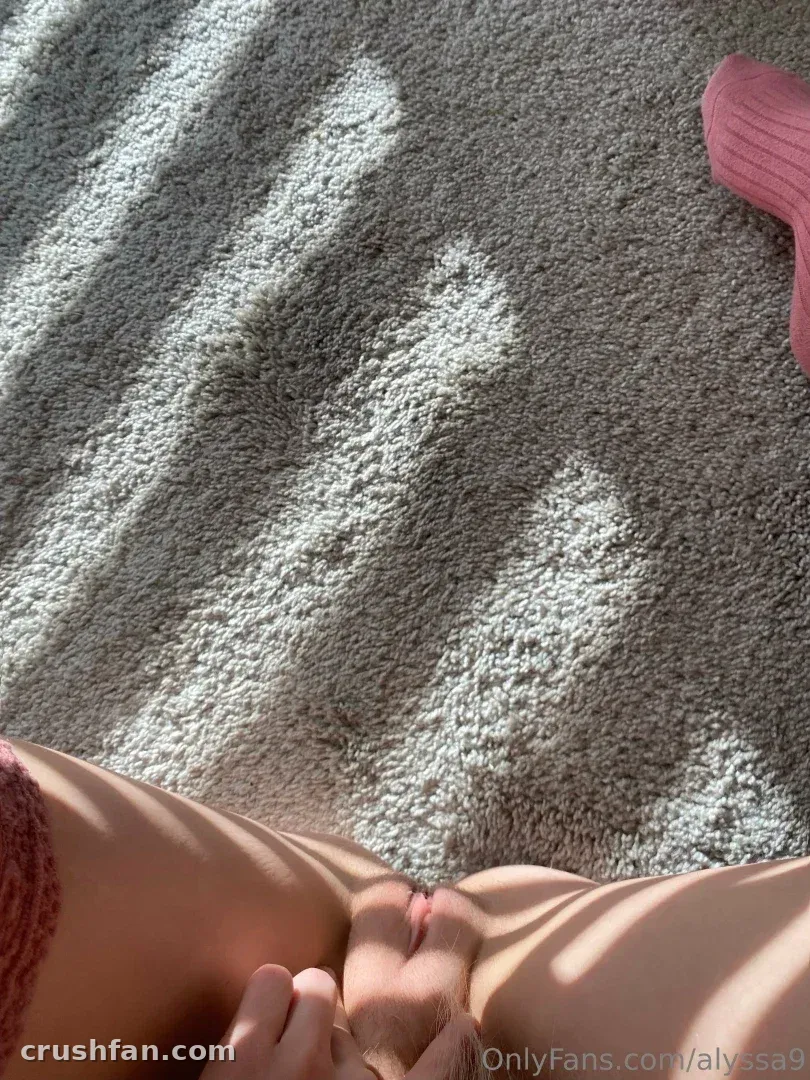 Gros plan ensoleillé d'une personne allongée sur une moquette grise avec un tissu rose à proximité