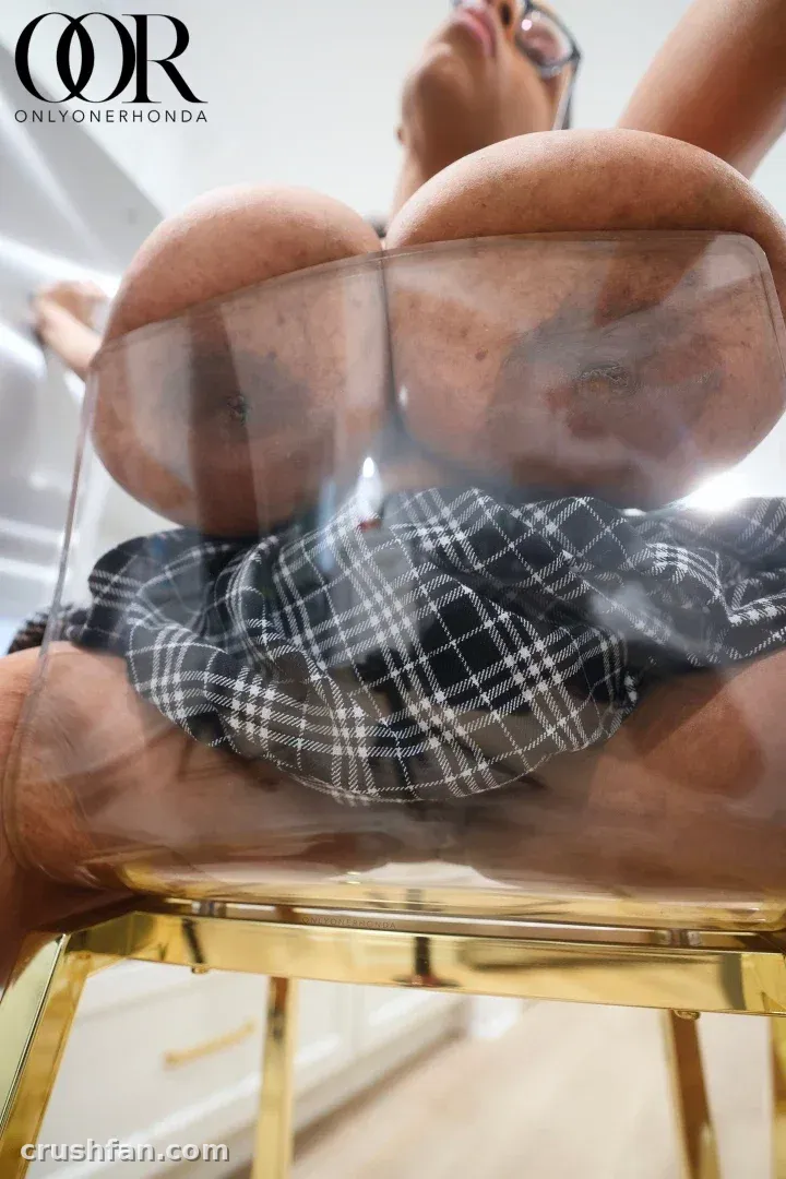 Creator in a plaid shirt viewed through the clear soles of her high heels indoors.