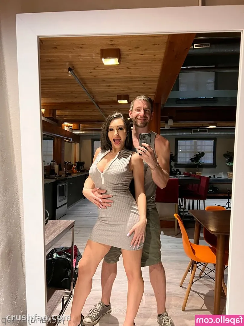 Creator in einem grauen Kleid beim Spiegel-Selfie in einem holzgetäfelten Raum mit orangefarbenen Stühlen.