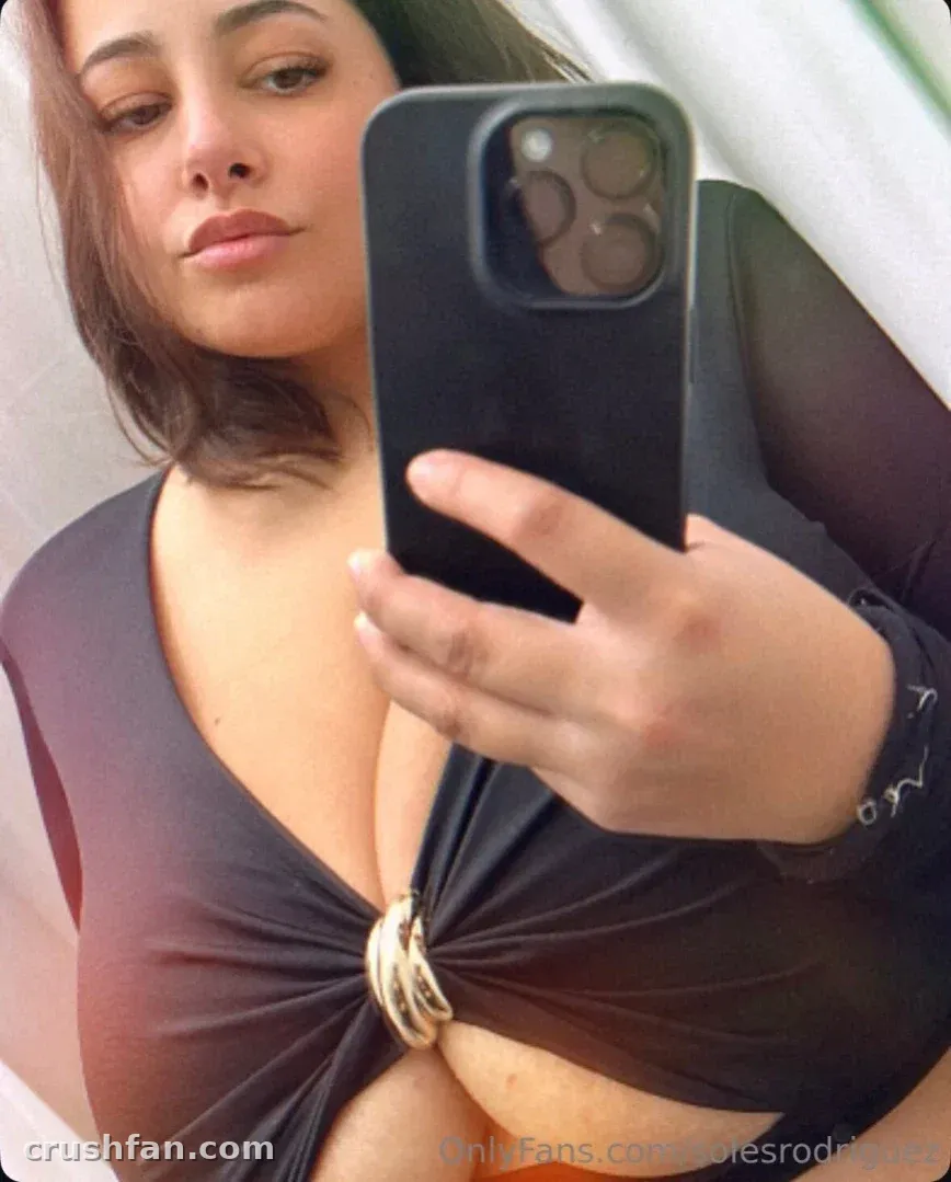 Soles Rodriguez taking a mirror selfie in a black top with a gold ring detail.