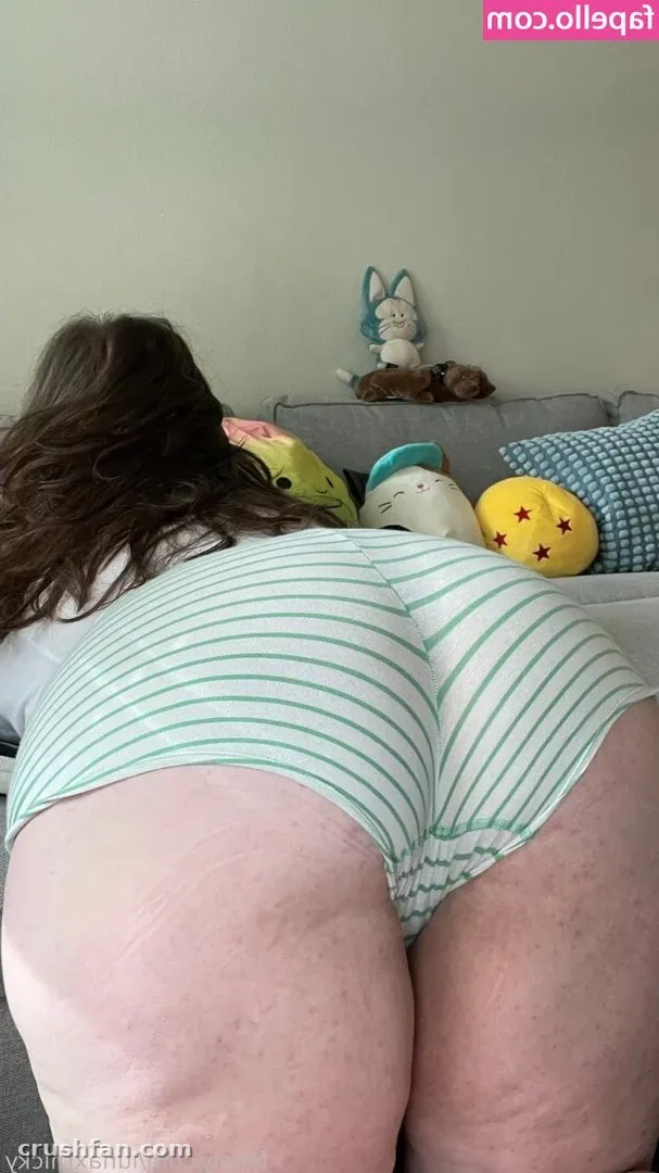 Luna inclinada sobre un sofá gris con shorts de rayas junto a peluches pastel