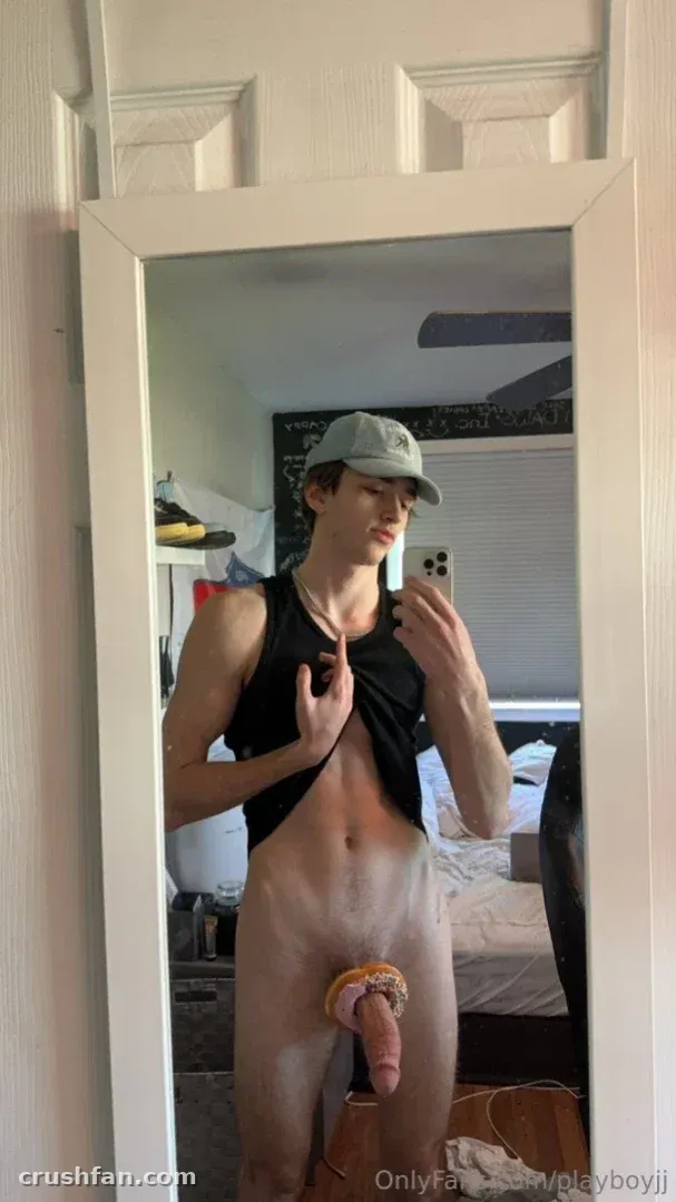 Jayden in a grey cap and black tank top taking a mirror selfie in a bedroom