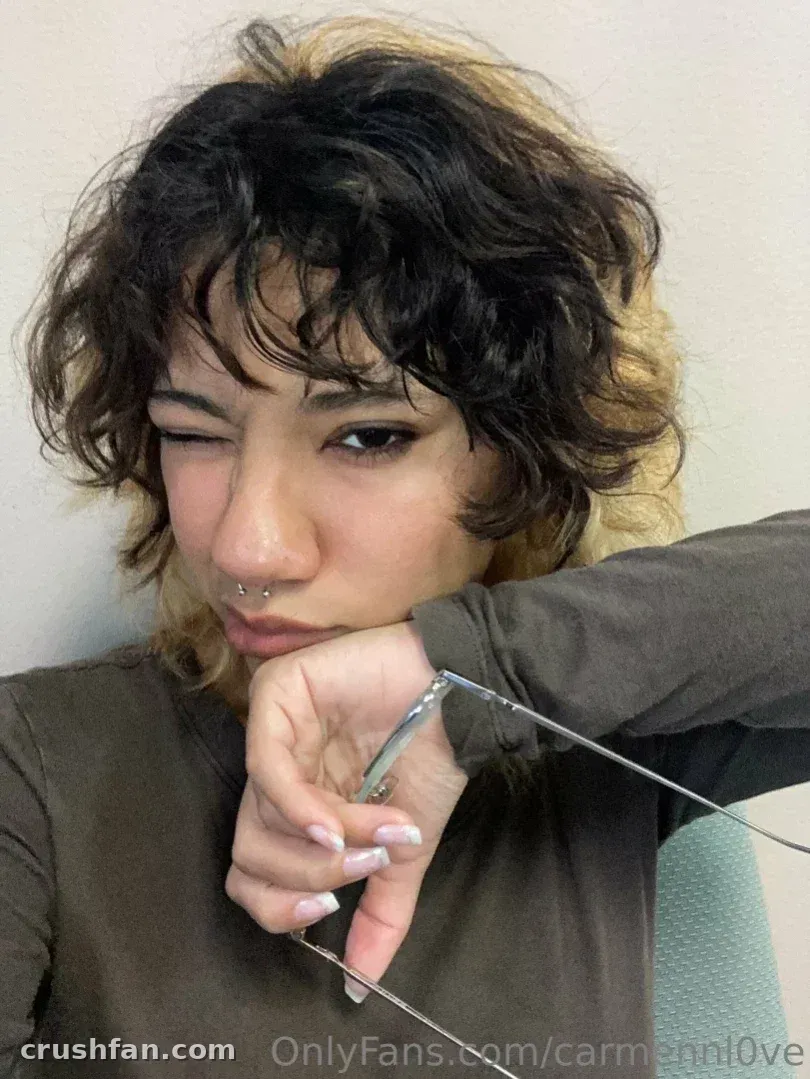 La oficial Carmen Love guiña un ojo mientras sostiene un cordón fino en una selfie en primer plano en interiores.