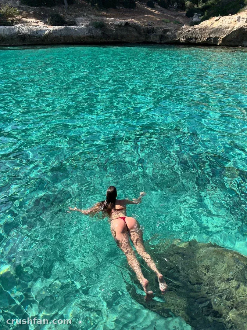Leena Hakkinen flottant dans une eau turquoise claire près d'une côte rocheuse