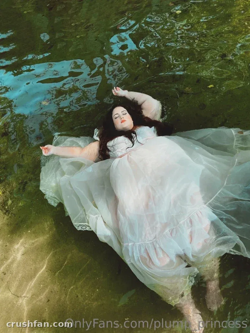 Plump Princess dans une robe pâle flottant sur une eau verte, vue d'en haut.