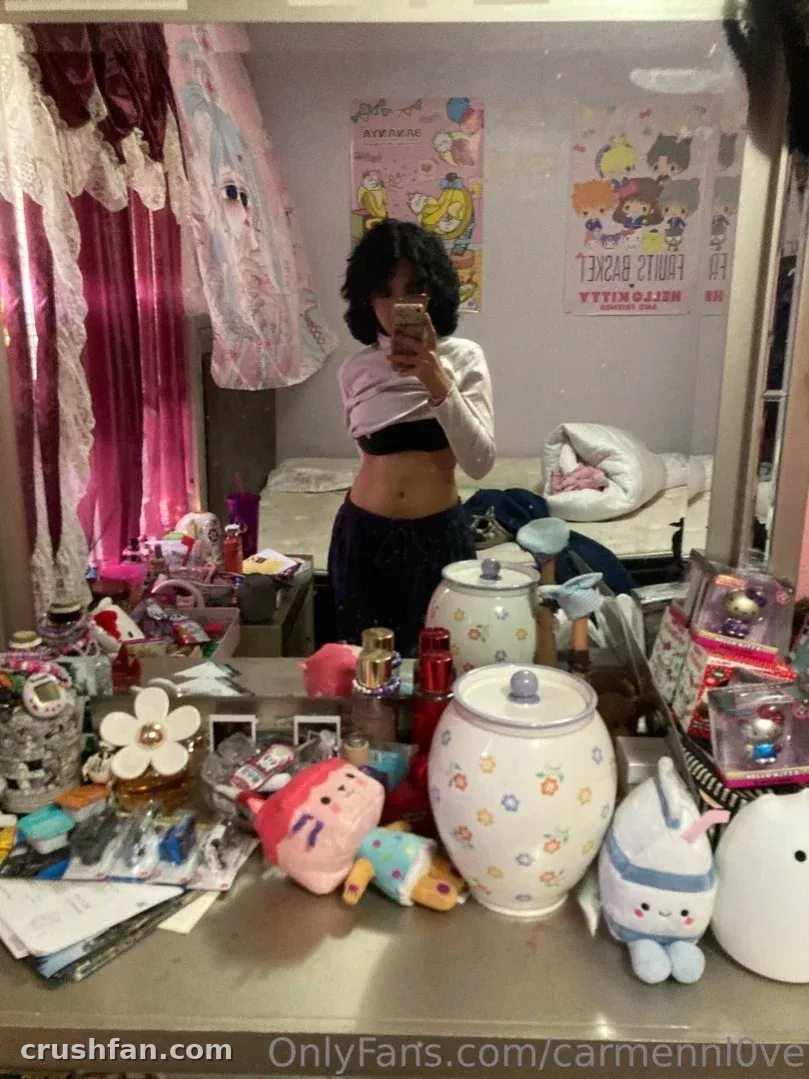 Creator in a light top and dark trousers taking a mirror selfie in a cosy bedroom.