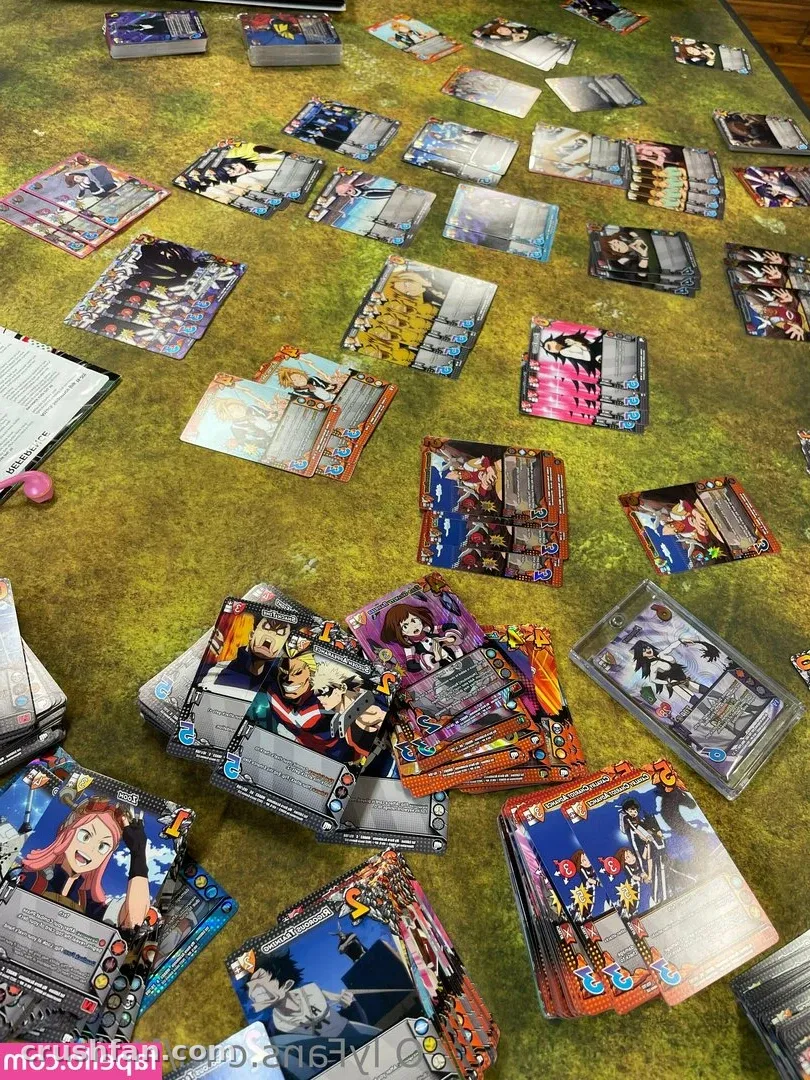 Trading cards spread across a green table beside a printed sheet and a small pink object