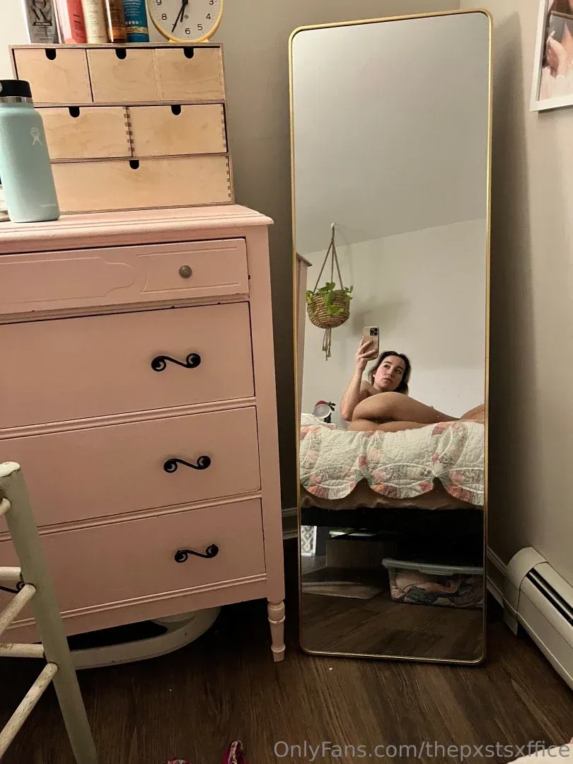 Maizie taking a mirror selfie in a bedroom with a pink dresser and hanging plant