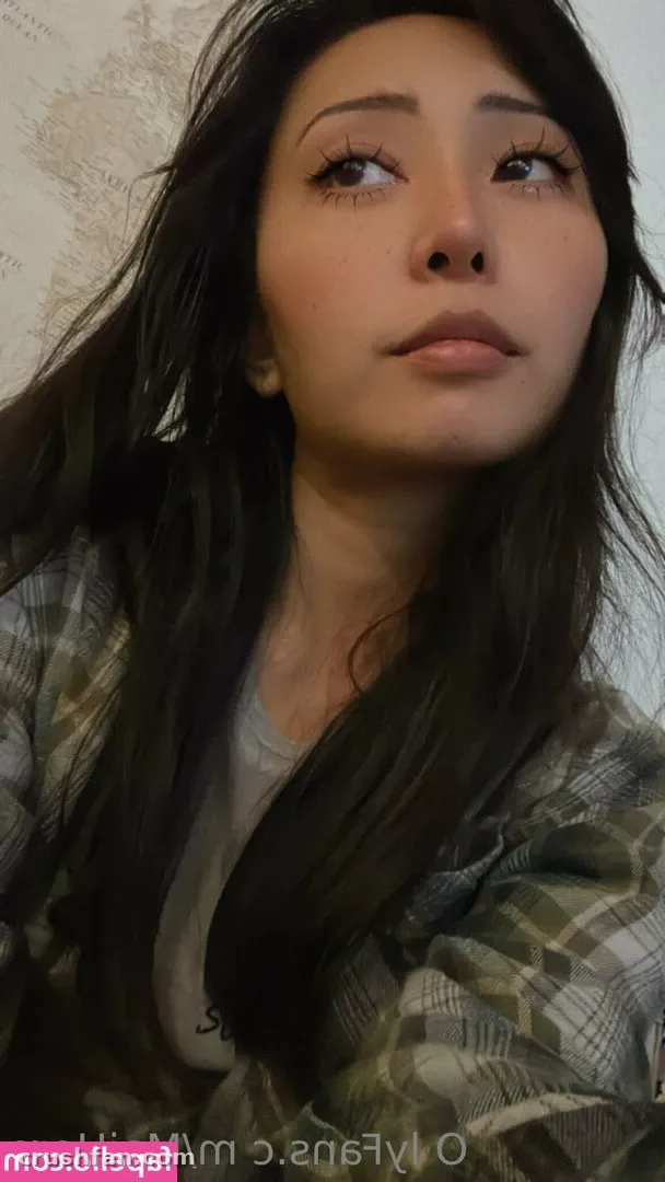 Retrato de close em ambiente interno de MaiHero com uma camisa xadrez olhando para cima