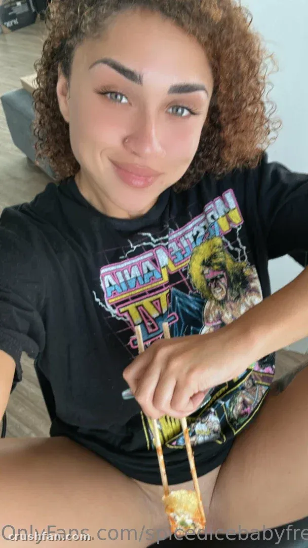 Spiced Ice Baby in einem schwarzen Grafik-T-Shirt, das Essstäbchen mit Essen hält.