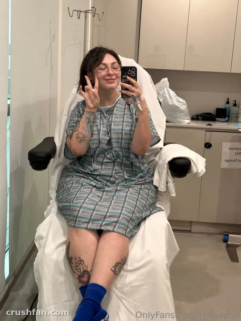 Creator in a striped gown taking a mirror selfie in a clinic chair
