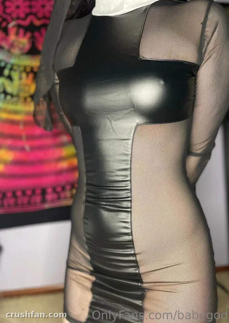 Vista cercana de un vestido negro brillante con paneles de malla transparente sobre un fondo de rayas coloridas