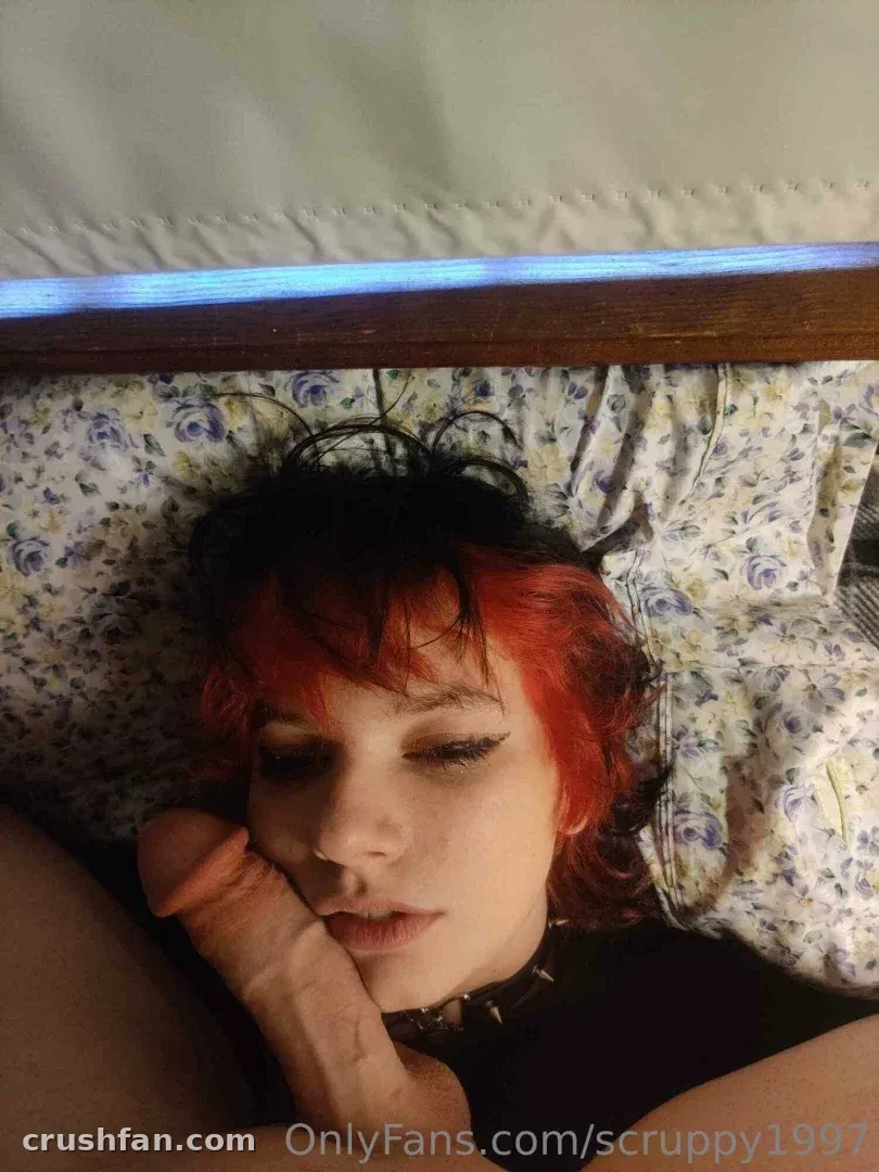 Creator with red-tipped dark hair and a spiked collar resting on floral bedding