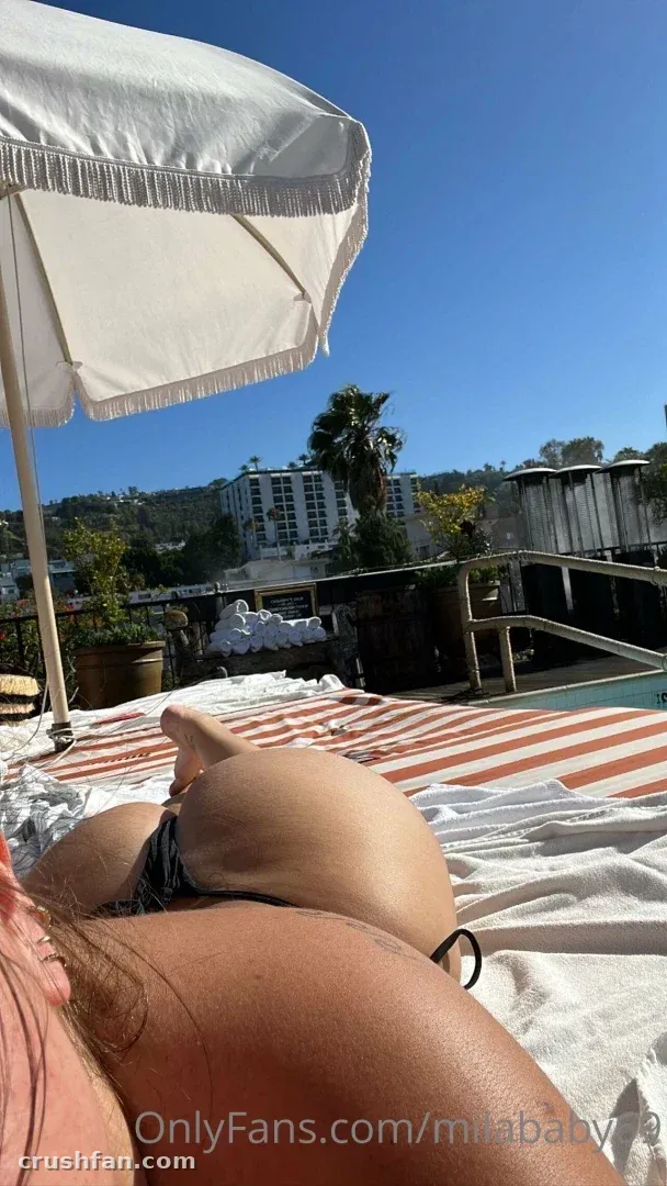 Mila ☆ Baby lying on a striped towel under a white umbrella on a sunny terrace