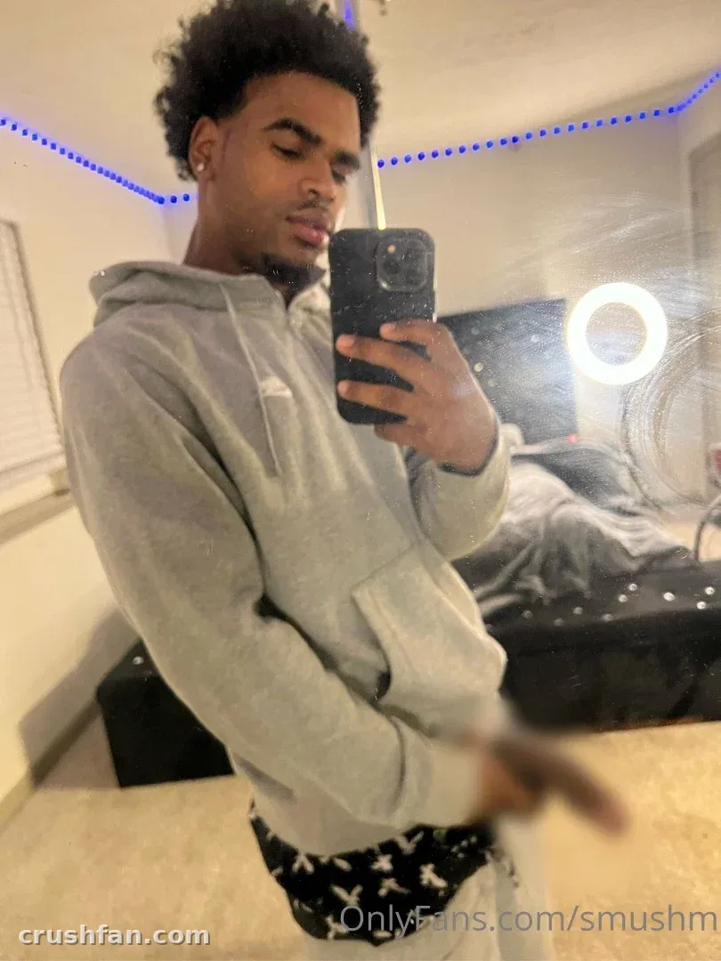 Creator in a grey hoodie taking a mirror selfie indoors with blue string lights.