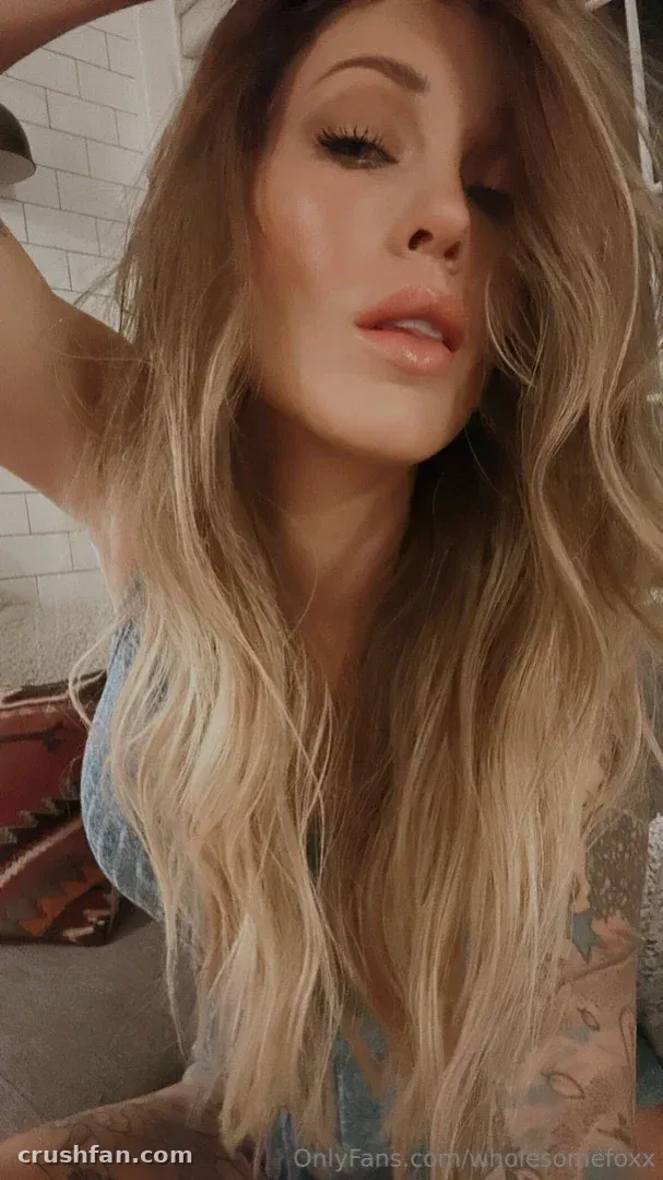 Wholesome Fox mit langem, welligem blonden Haar in einem hellblauen Top drinnen