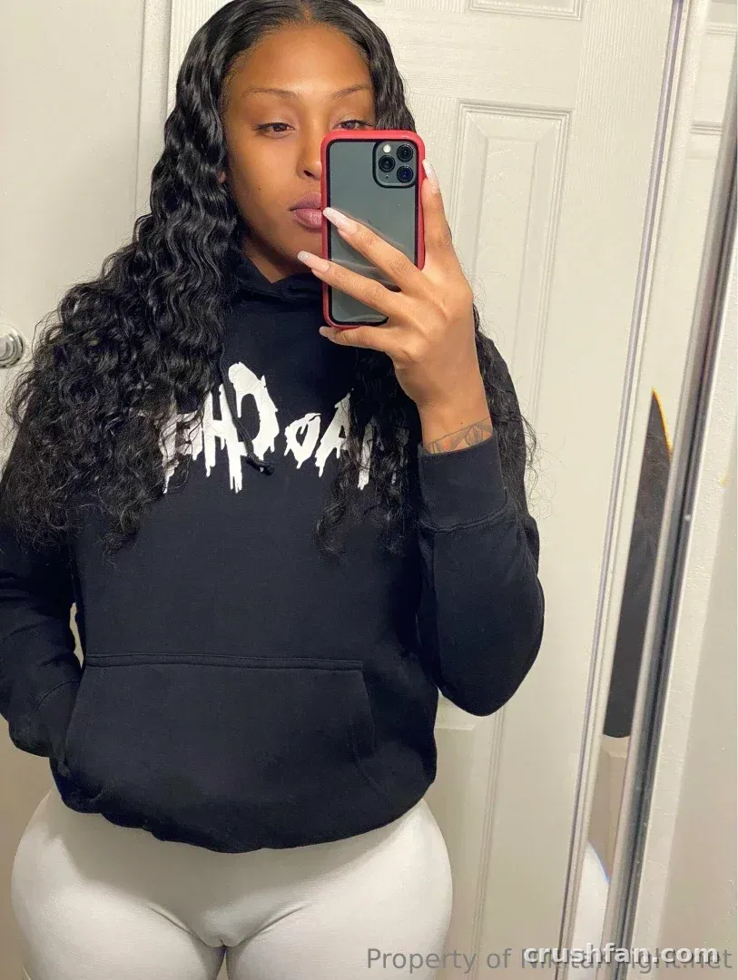 NikitaKnight taking a mirror selfie in a black hoodie and grey leggings.