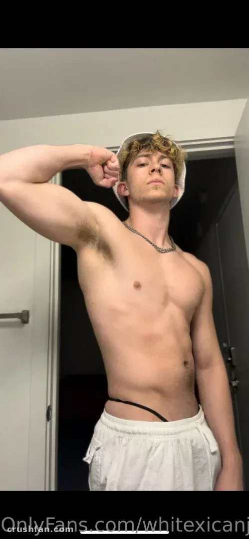 Creator flexing in a doorway wearing white shorts and a chain necklace.