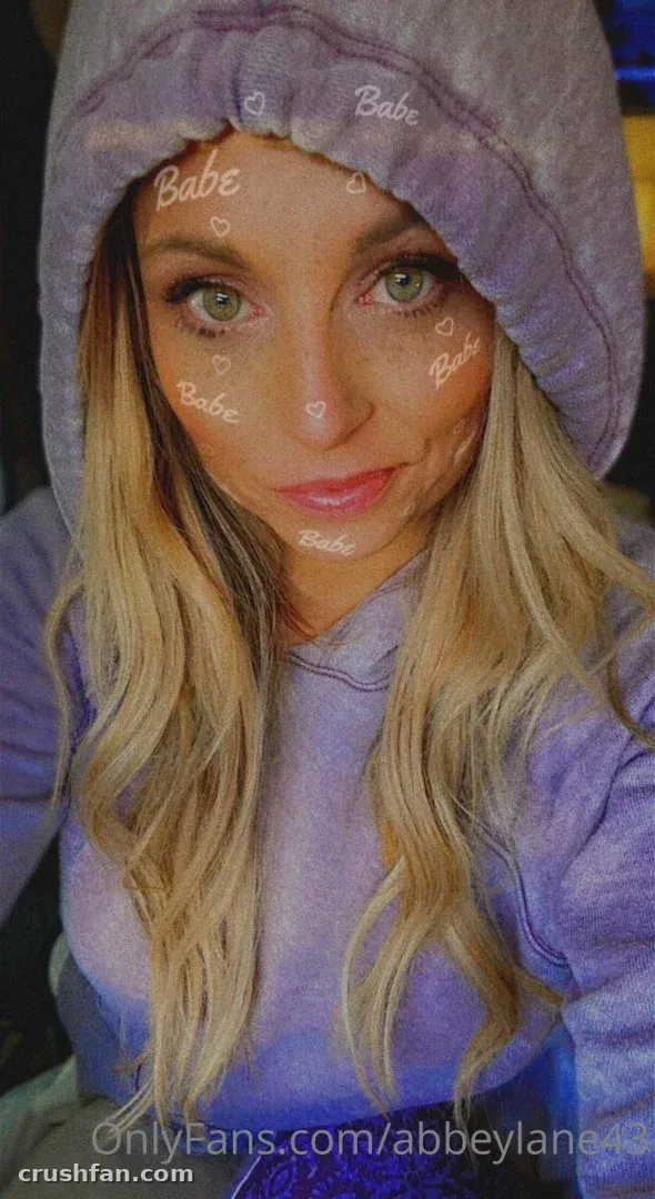 Close-up selfie of a woman in a lilac hoodie with text overlay across the frame