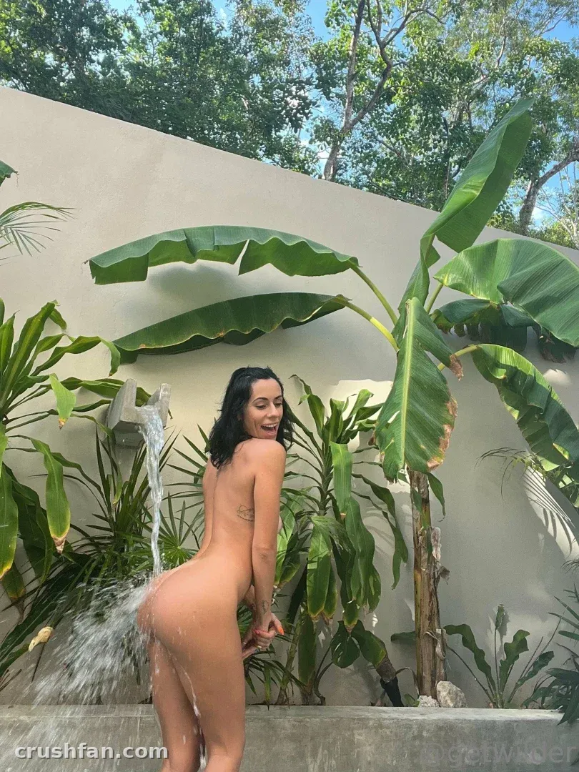 Get wild standing outdoors among large tropical leaves beside a water feature