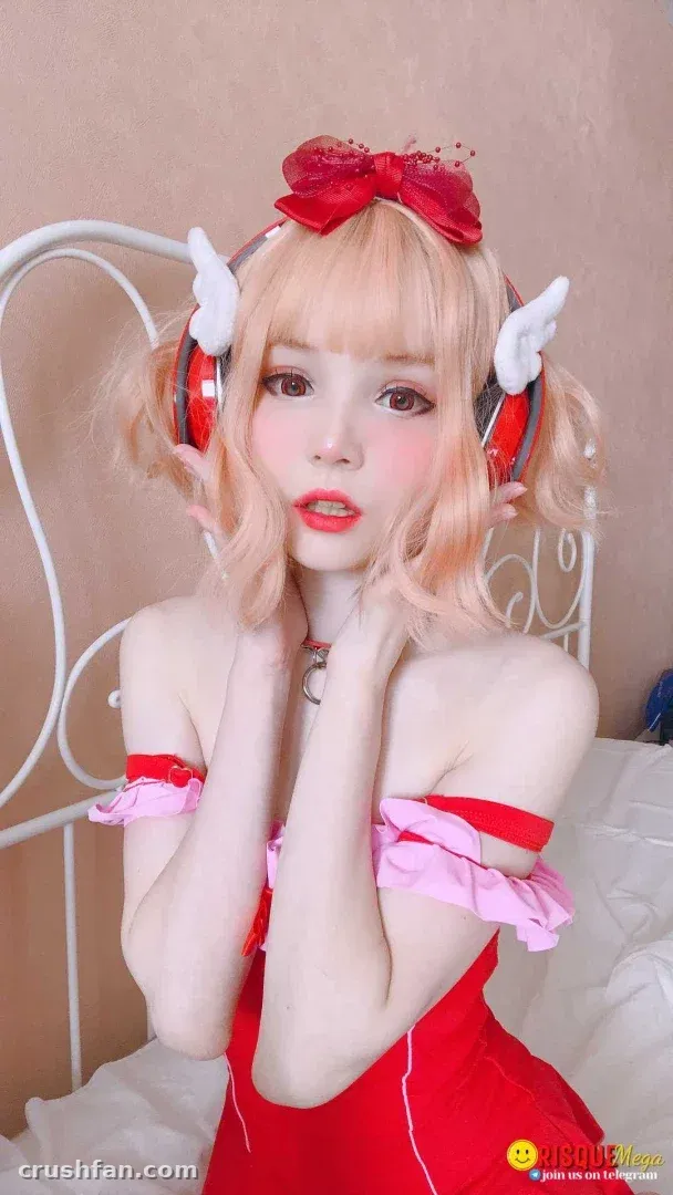 Alisa in a red bow and red headphones, wearing a red top with pink ruffled sleeves indoors