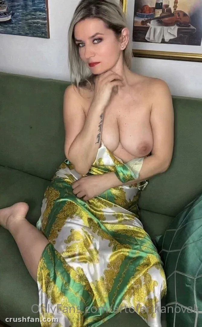 Bad Ery seated on a green sofa wearing a green and gold patterned robe