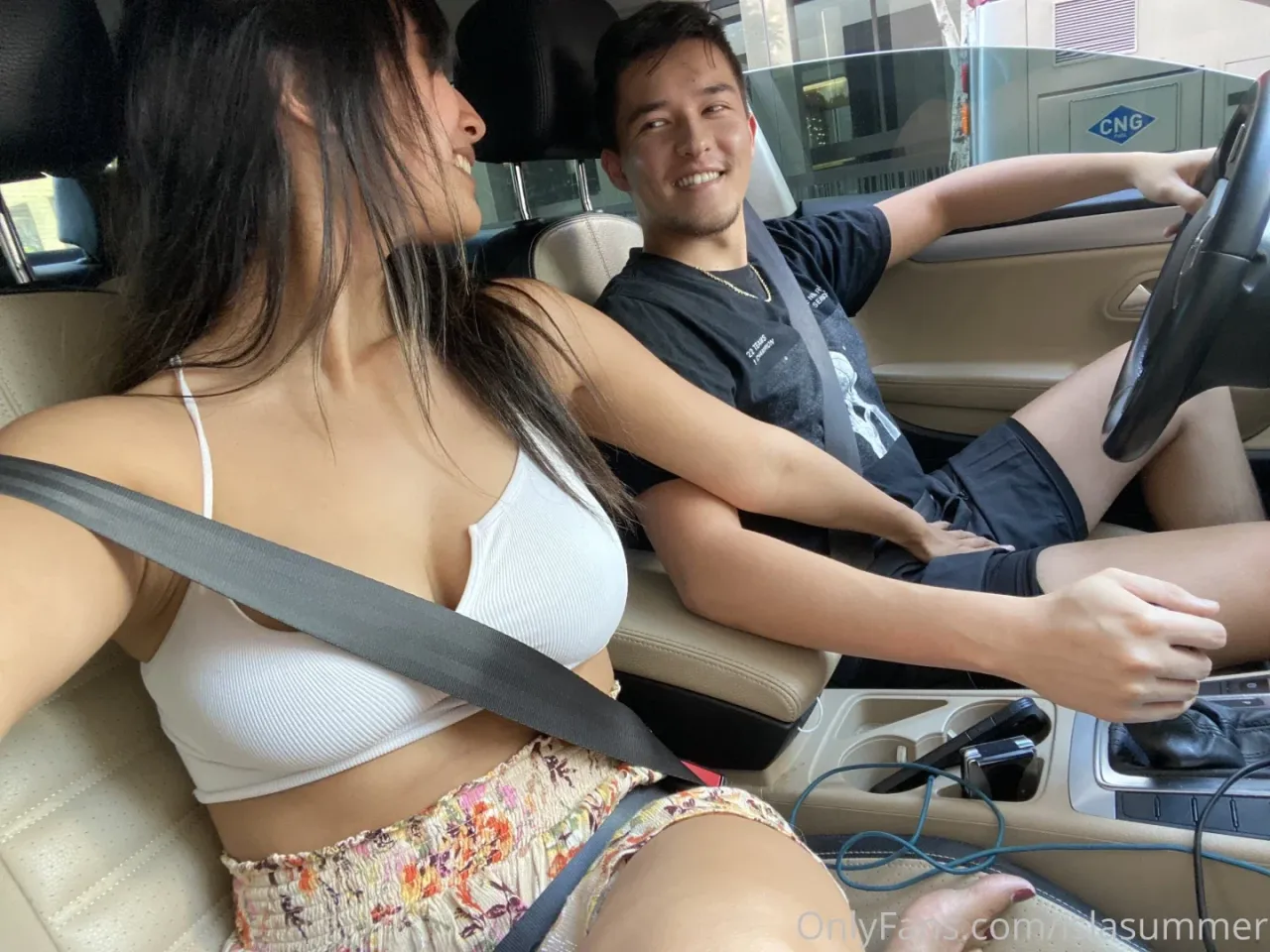 Isla Summer в белом топе и юбке с цветочным принтом сидит на пассажирском сиденье автомобиля