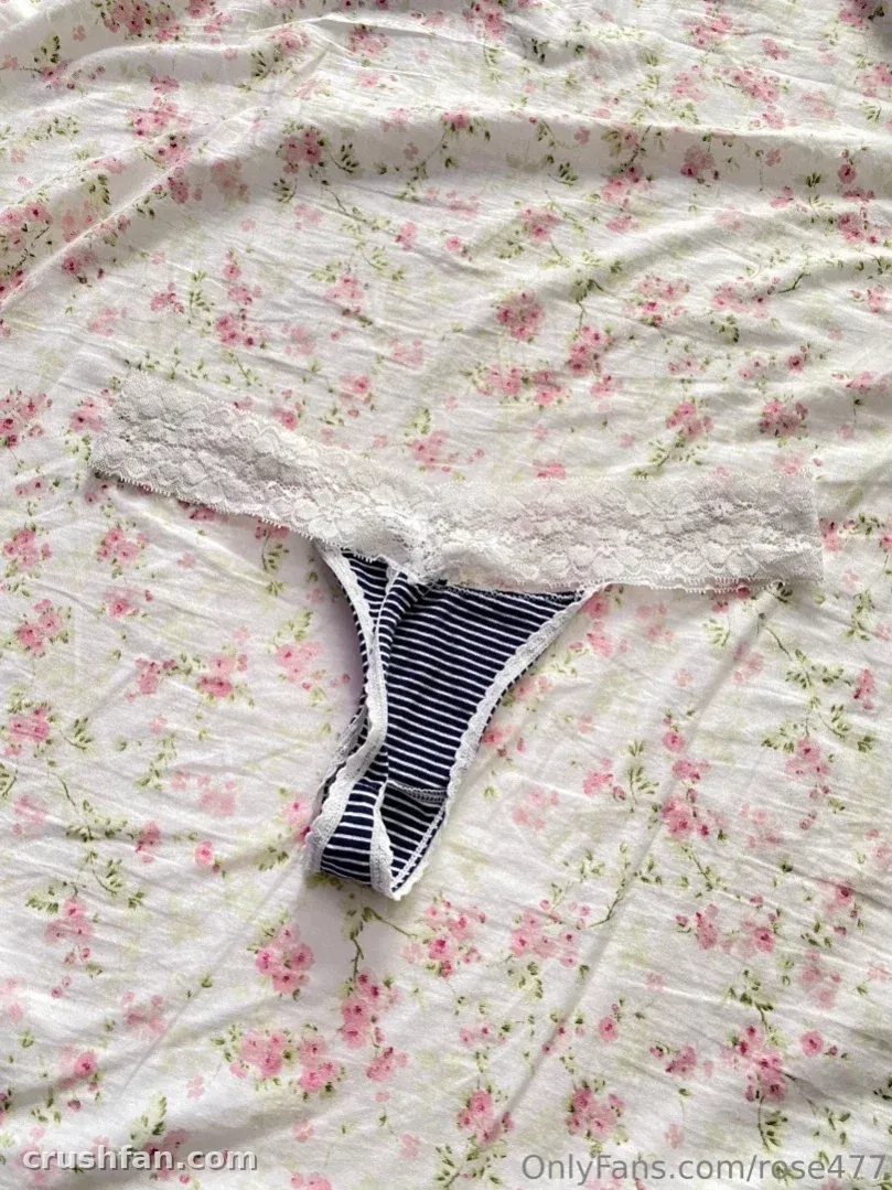 Primer plano de lencería de encaje floral y bragas a rayas sobre una sábana floreada.