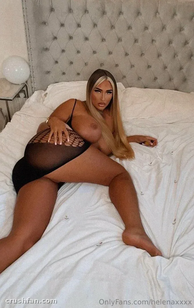 Helena in black lingerie lying on a white bed with a tufted headboard