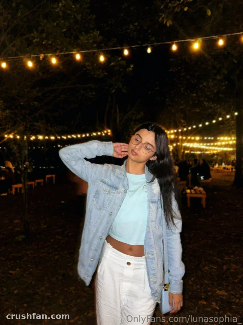 Mulher de jaqueta jeans em pé sob luzes de cordão à noite