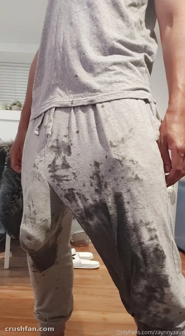 Creador con parte superior sin mangas gris y pantalones jogger con manchas oscuras, visto desde atrás en interiores