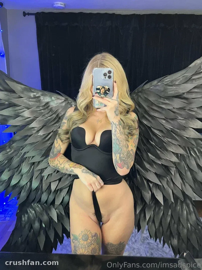Liz in black lingerie with dark feathered wings taking a mirror selfie