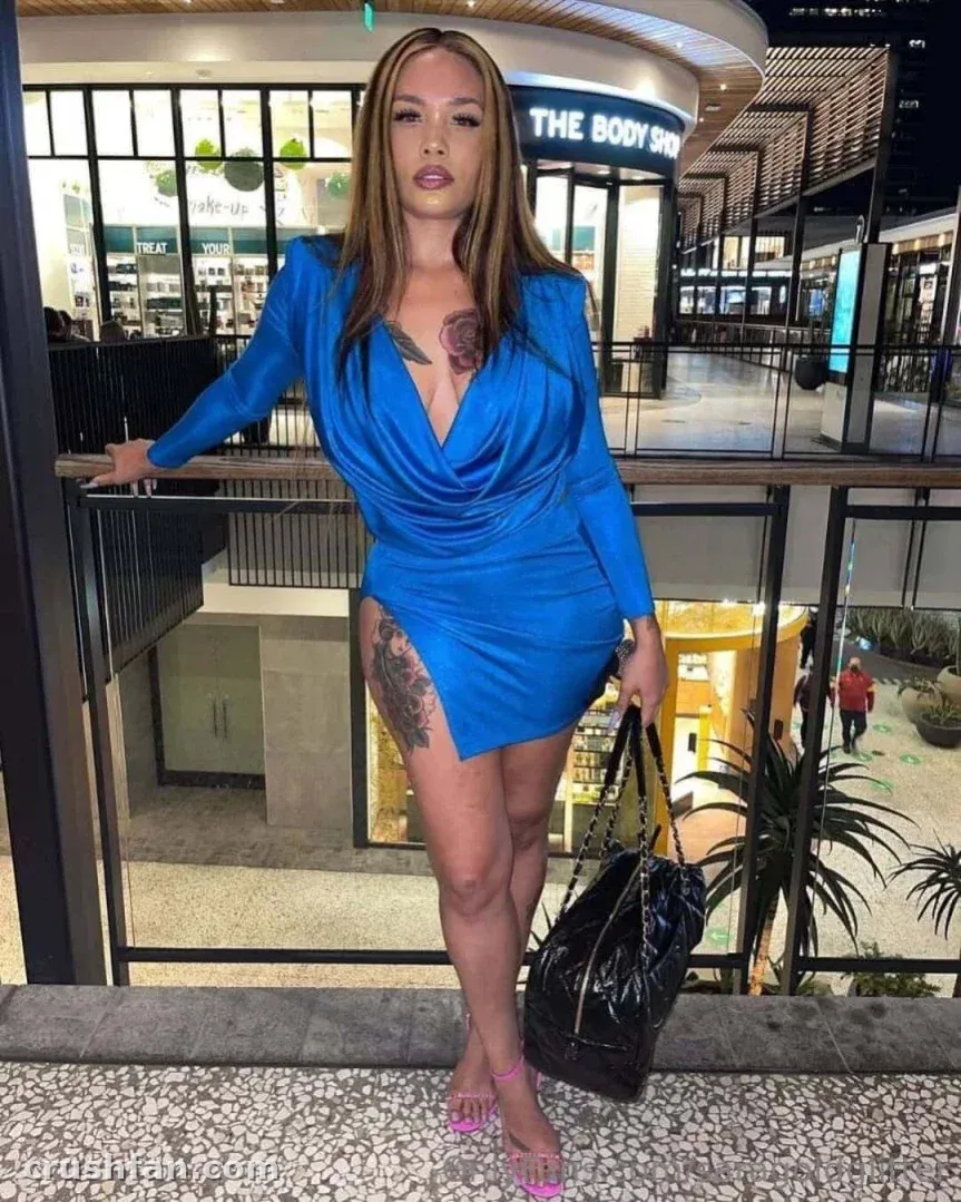Sara Gold con un vestido azul apoyada en una barandilla dentro de un centro comercial