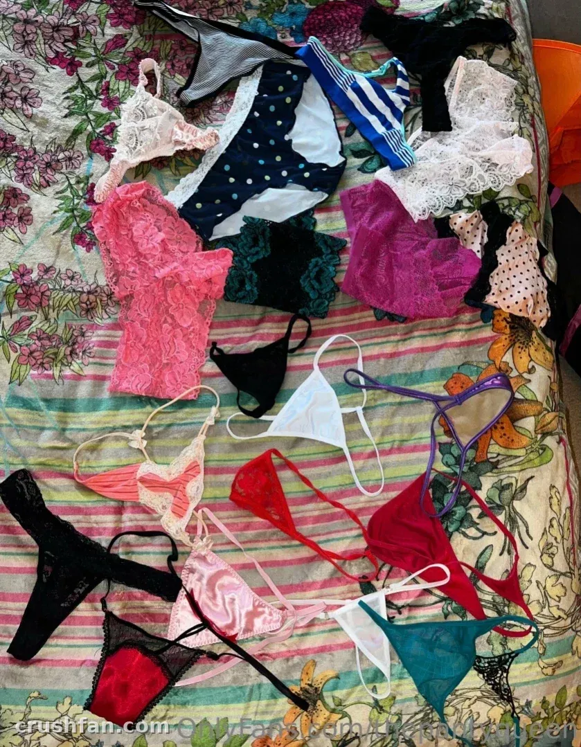Assorted lace and mesh lingerie in pink, black and teal arranged on a floral striped bedspread