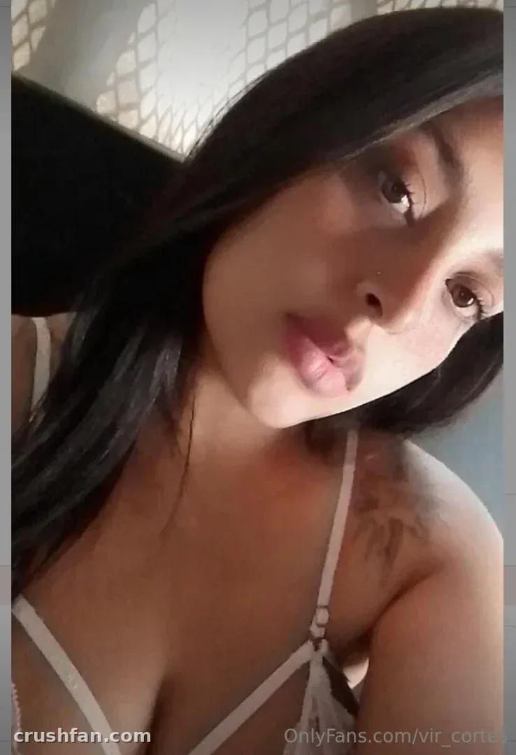 Virginia prend un selfie en gros plan à l'intérieur avec un éclairage doux et de longs cheveux foncés.