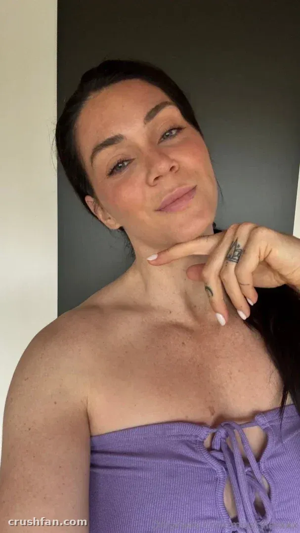 Alison Tyler con un top lila sin tirantes tomando un selfie de cerca en interiores