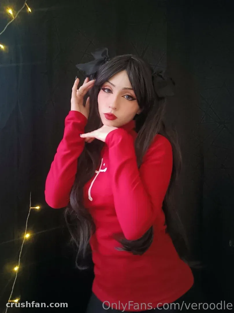 Creator in a red high-neck top and black hair bows posing by warm fairy lights