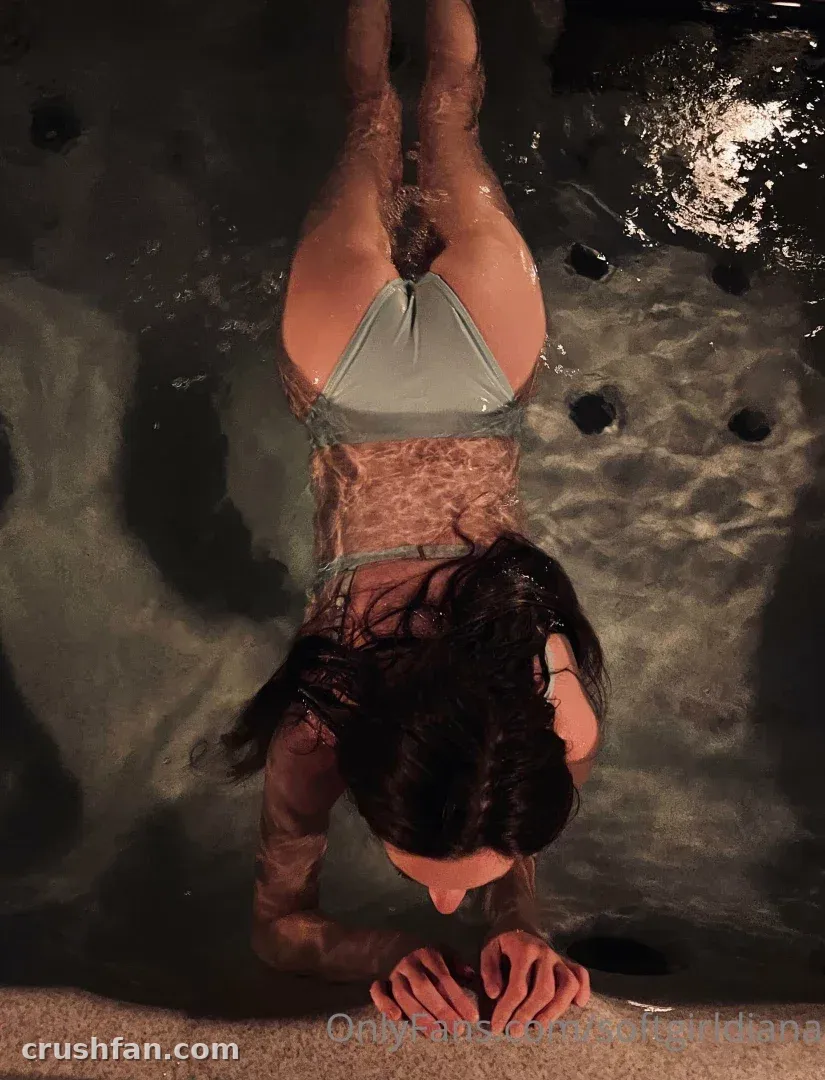 Creator in a bikini leaning on the edge of a dark stone pool