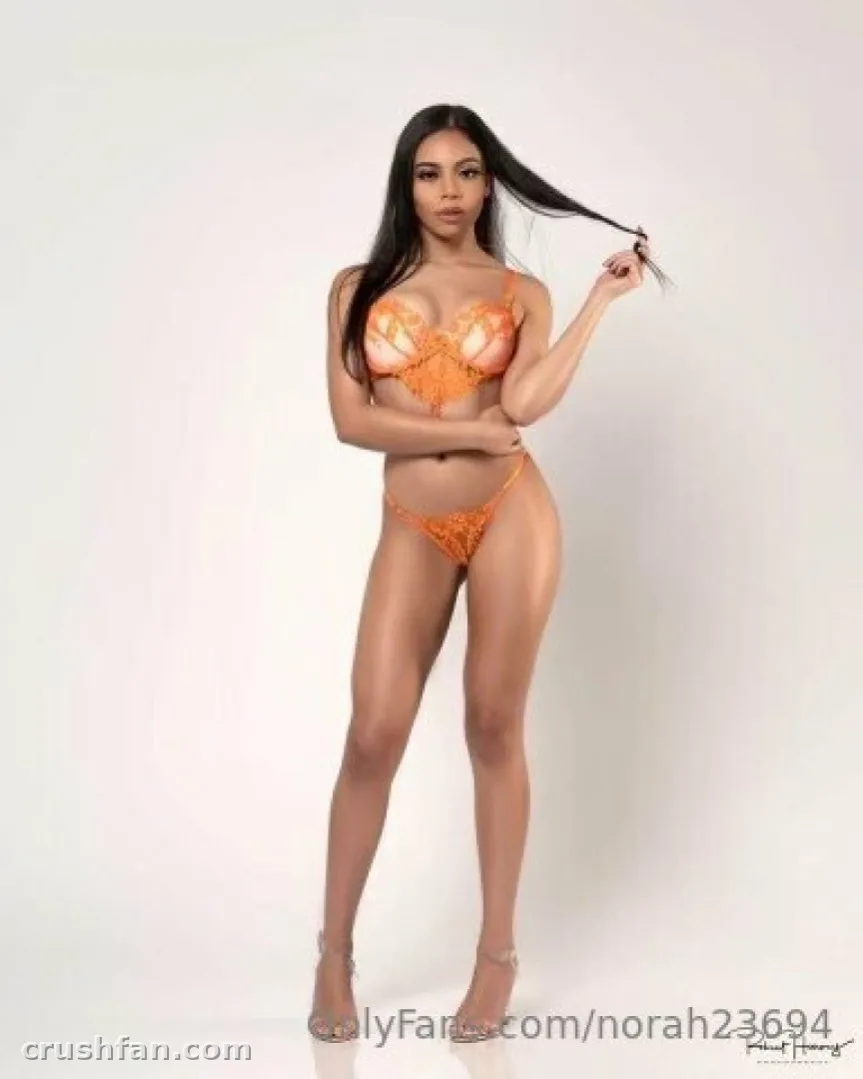 Criadora em lingerie de renda laranja em pé sobre fundo de estúdio branco