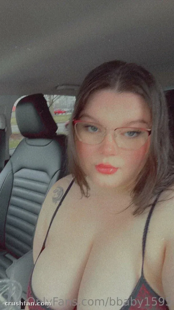 Miss Bunny in einem Auto mit Brille und einem dunklen Top, die in die Kamera blickt.