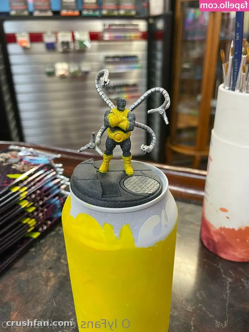 Yellow can topped with a small figure, comic shop shelves blurred behind