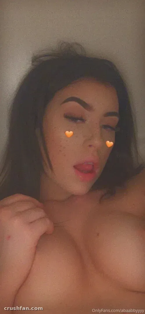 Nahes Indoor-Selfie einer Frau mit dunklem Haar und Herzstickern auf den Wangen