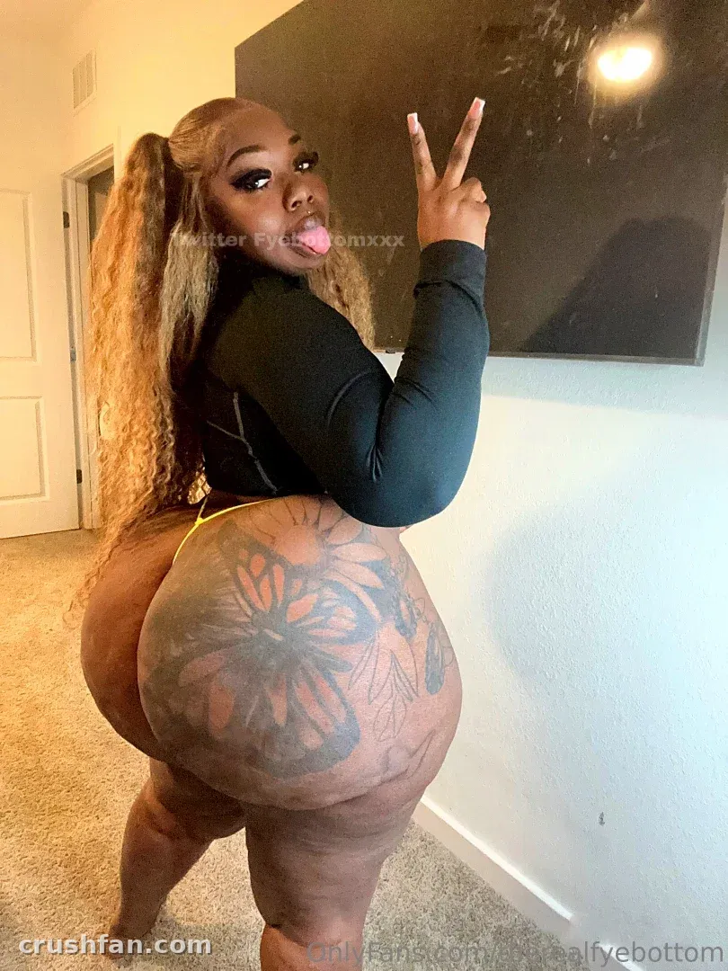 Fyebottom com um top preto em ambiente interno, fazendo um sinal de paz com uma tatuagem floral visível.