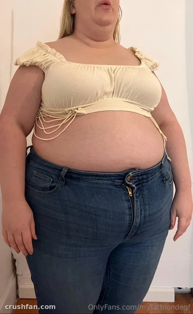 Creator in a cream off-shoulder top and blue jeans against a white wall