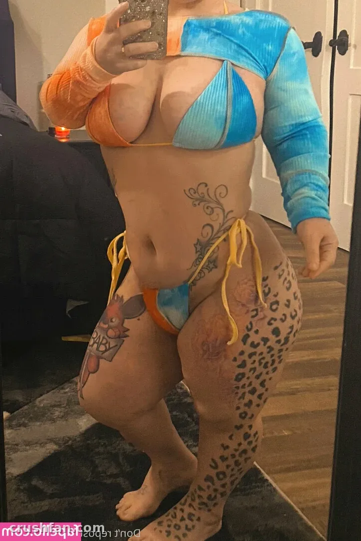 Creadora con un conjunto de dos piezas azul y naranja tomándose una selfie frente al espejo en interiores