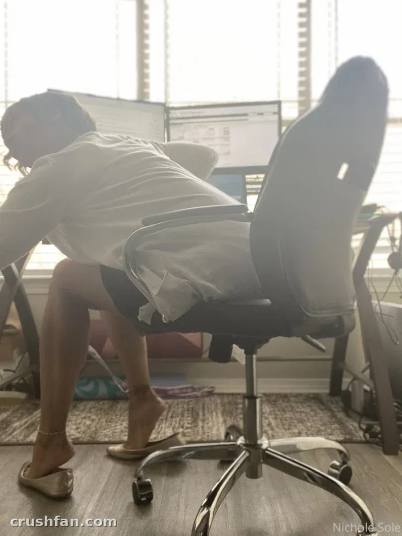Nichole Sole sentada en una silla de oficina en un escritorio en una habitación luminosa