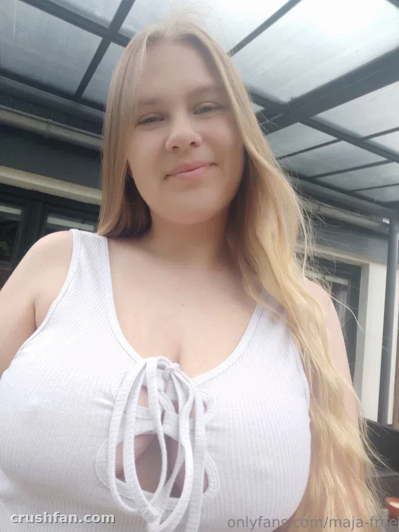 Maja-Meer smiling in a white lace-up tank top beneath a glass roof