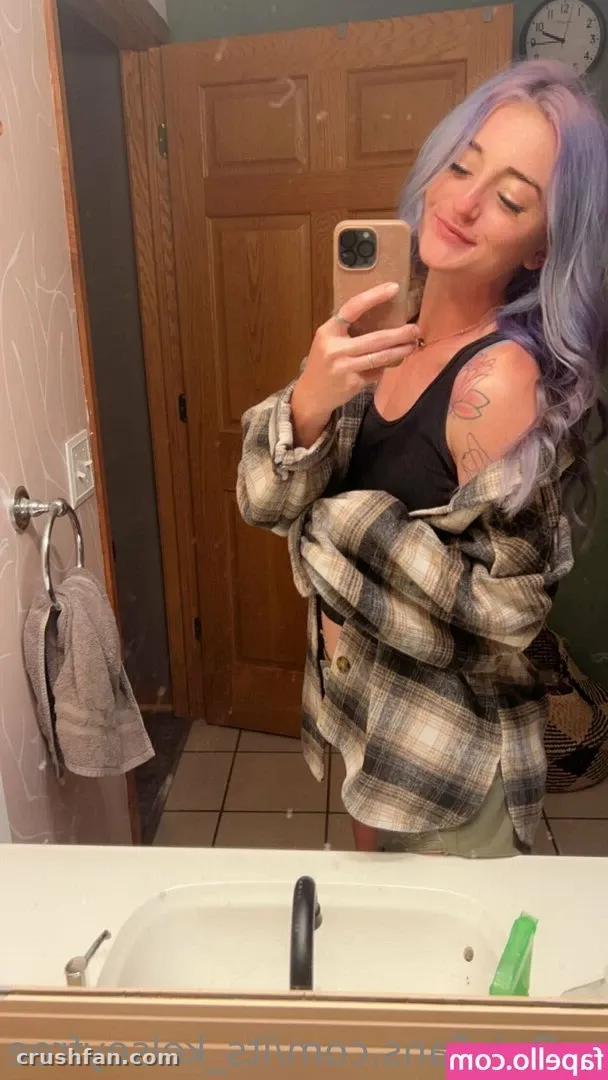 Kelsey Anne in a plaid shirt taking a mirror selfie in a bathroom