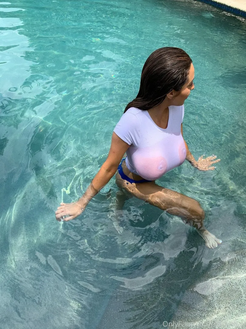 Danielley Ayala standing in a turquoise pool wearing a wet white top and blue bikini bottoms